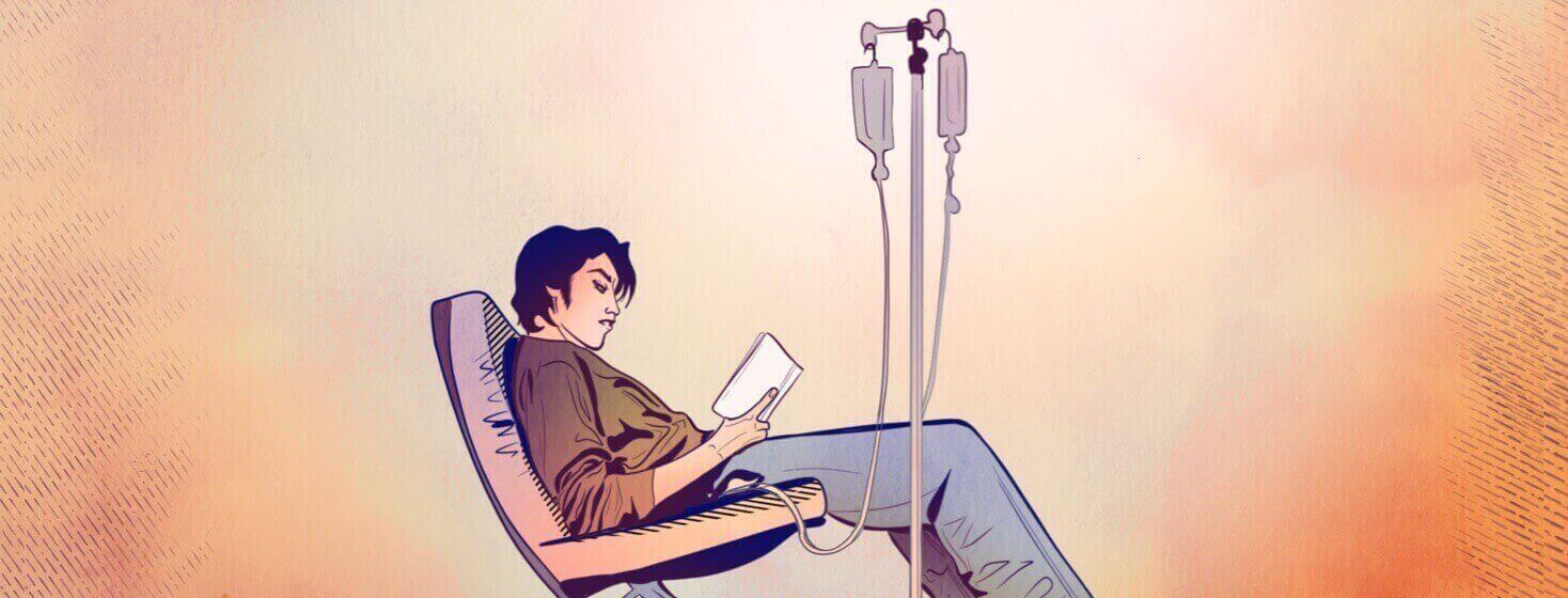 A man sitting in a recliner chair reads a book while getting an infusion from an IV